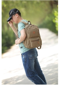 Outdoor shot of khaki canvas backpack with multiple pockets on a park path