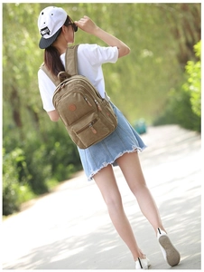 Detail of vintage khaki canvas backpack showing dual front zipper pockets and leather pulls