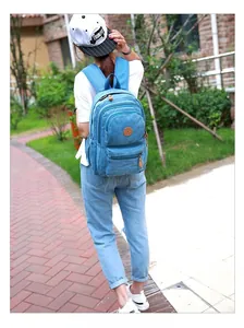 Sky blue washed canvas backpack detail featuring multiple zipper compartments and leather logo