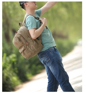Outdoor lifestyle shot of a khaki canvas backpack featuring leather zipper pullers
