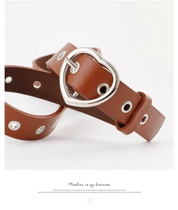 Close-up of a brown leather belt featuring a silver heart buckle and metal grommets