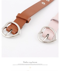 Close-up of heart-shaped metal buckles on brown and pink leather belts for women