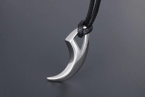 Detailed view of polished silver crescent moon wolf tooth pendant on black braided cord