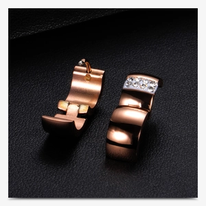 Detail of rose gold titanium steel hoop earrings with white zircon stone inlay