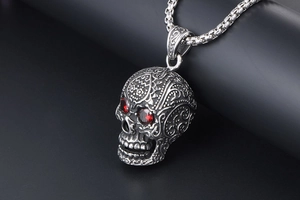 Detailed close-up of a silver punk skull pendant with striking red stone eyes