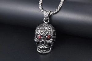 Macro shot of silver skull pendant featuring red gemstone eyes and intricate carvings