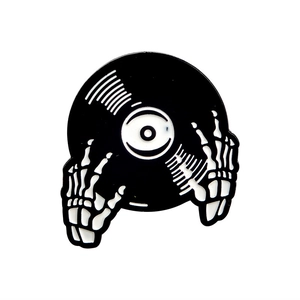 Enamel pin featuring skeleton hands holding a vinyl record in black and white finish