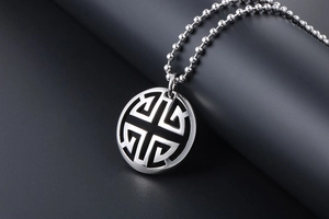 Detailed view of silver hollow circular pendant necklace with geometric pattern on bead chain