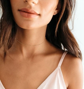 Primo piano della collana minimalista in ottone placcato oro 18K indossata sul collo
