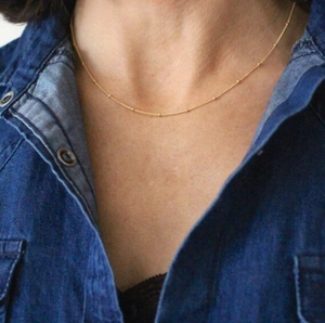 Primo piano di una delicata collana a catena con perline in ottone placcato oro 18K