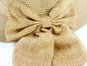 Détail d'un chapeau de paille tissé avec un grand nœud texturé et un savoir-faire en fibres fines
