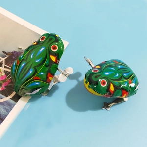 Classic green tin wind-up jumping frog toys with nostalgic retro patterns on blue background