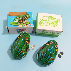 Close-up of classic wind-up tin frogs with colorful vintage patterns and retro paper boxes