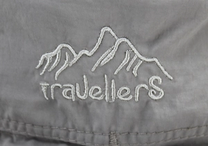 Détail de la broderie travellerS et des montagnes sur le tissu gris du chapeau d'été