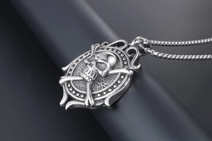 Macro detail of a vintage silver skull and crossbones pendant with an embossed oval frame