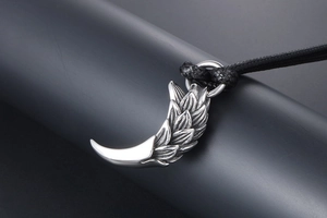Macro shot of silver dragon scale feather pendant with black woven cord necklace