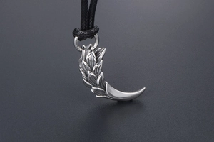 Macro shot of silver tiger tooth pendant with feather engraving and black rope