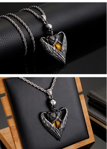Detailed view of skull pendant with angel wings and amber gemstone on rope chain