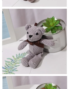 Close-up of a grey checkered teddy bear with a brown bow in a cozy home setting