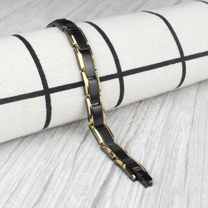 Close-up of black and gold magnetic therapy bracelet on a checkered fabric roll