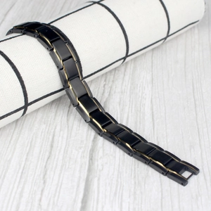 Detail of black and gold titanium steel magnetic bracelet draped on a display stand