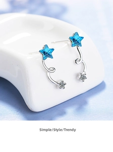 Macro shot of S925 sterling silver blue crystal star earrings on white ceramic base