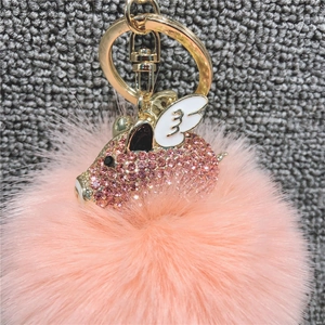 Dettaglio ravvicinato di un portachiavi a maialino volante con strass rosa e oro