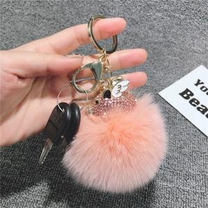 Dettaglio portachiavi pompon rosa con maialino volante in cristallo su anello d'oro
