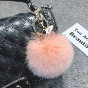 Dettaglio portachiavi pompon rosa con maialino dorato su borsa trapuntata nera