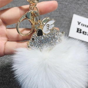 Primo piano del portachiavi a maialino dorato con strass scintillanti e pompon bianco