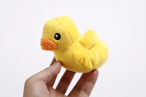 Detail view of small yellow plush duck toy held in hand showing compact size and texture