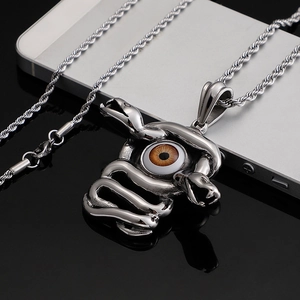 Punk style stainless steel snake necklace with evil eye pendant on reflective black surface