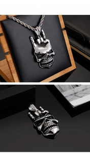 Gros plan d'un pendentif crâne argenté avec geste rock sur un support noir élégant