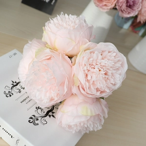 Close-up of pink silk peony bouquet with detailed petals on decorative book