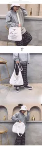 Detail view of large white canvas tote bag with artistic prints on casual model outfit