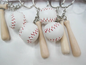 Close-up of mini baseball bat and leather ball pendants on silver keychain rings