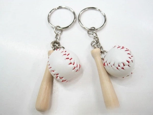 Detail view of mini baseball bat and leather ball with metallic ring on white background