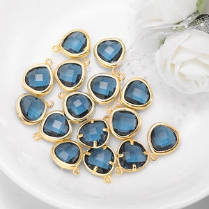 Pendenti in cristallo blu a goccia con bordo dorato in un piatto di ceramica bianca