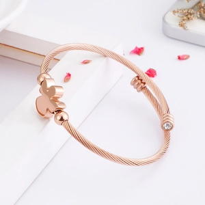 Rose gold twisted rope bangle featuring a lucky clover charm and round clear zircon stone