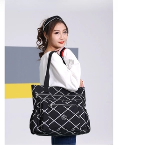 Detail of a black nylon shoulder bag with diamond pattern and large side pockets on model