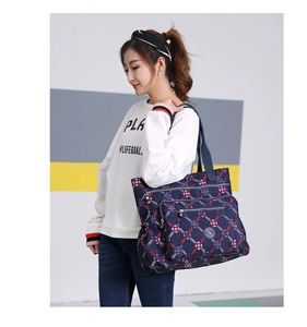 Detail view of large nylon shoulder bag with navy blue floral print and zipper pocket