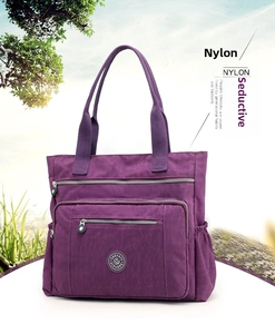 Detail view of purple nylon tote bag featuring multi-pocket design and circular rubber logo