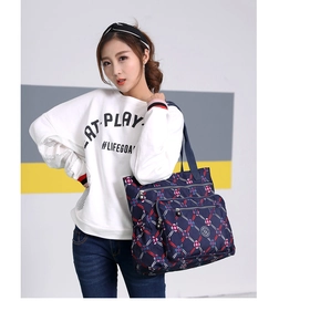Detail view of navy blue nylon shoulder bag with red and white geometric patterns