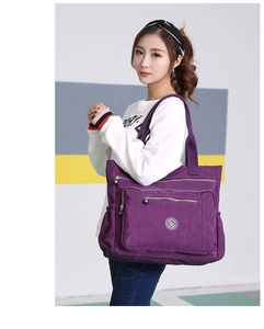 Detailed side view of purple nylon tote bag with multi-zipper pockets on model