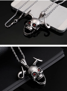 Detail of silver bull skull pendant with red gemstone eyes on a twist chain necklace