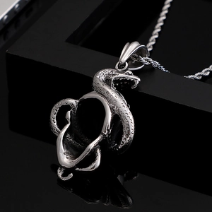 Punk style silver snake and skull pendant necklace on a reflective black background