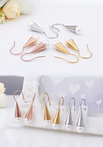 Chic shell pearl drop earrings in gold, silver and rose gold displayed on a stand