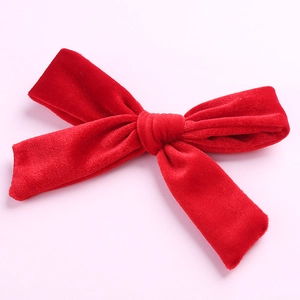 Detailed texture of red velvet bow hair clip with polished metal alligator clamp