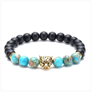 Macro detail of leopard head charm on black matte and turquoise stone beaded bracelet
