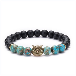 Detail of 8mm matte black and turquoise beads bracelet with a golden owl charm centerpiece